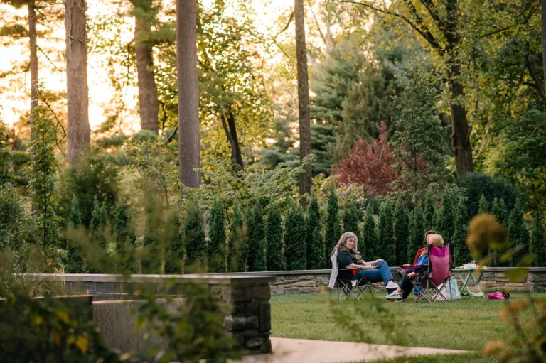 Two women picnicking at dusk in the gardens at Stoneleigh: a nutral garden